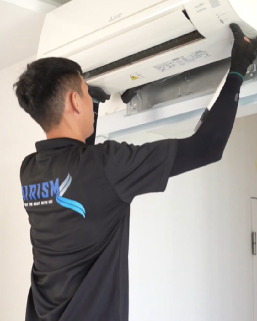 Technician servicing open air conditioning unit showing internal components