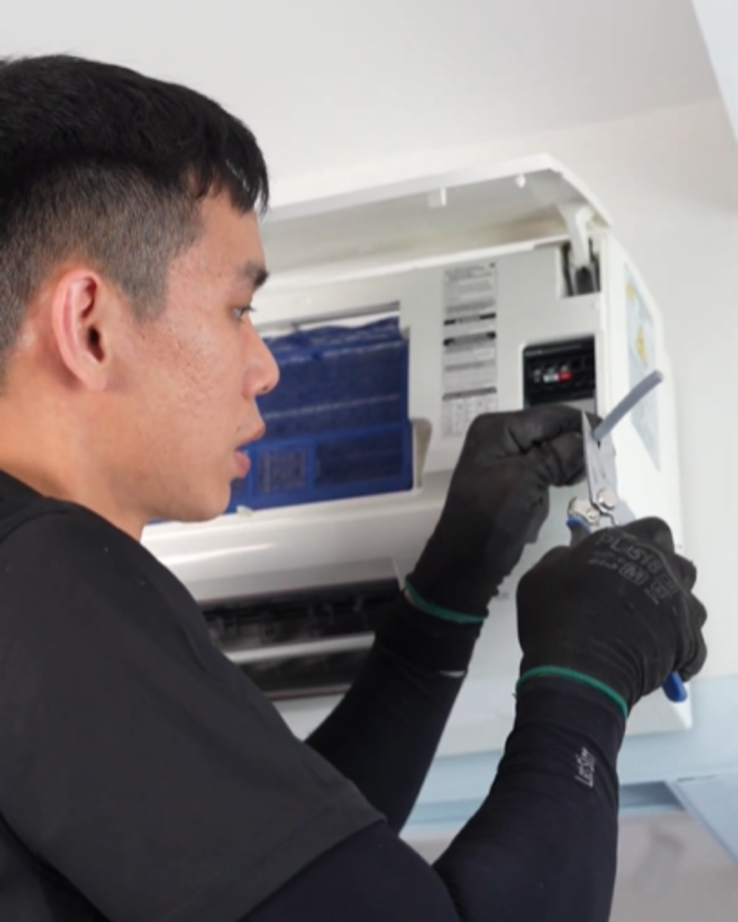 Close-up of technician using tools to inspect air conditioner electronics