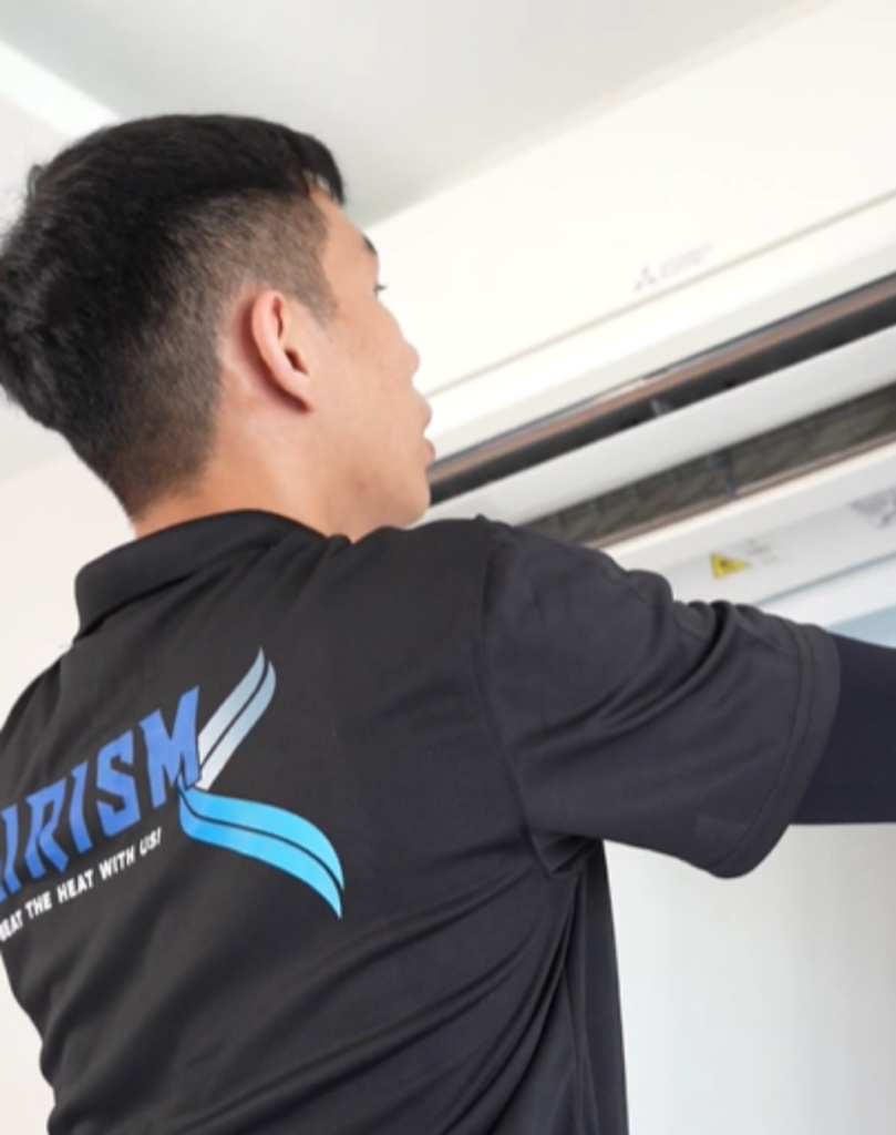 AIRISM technician examining wall-mounted air conditioner during maintenance service